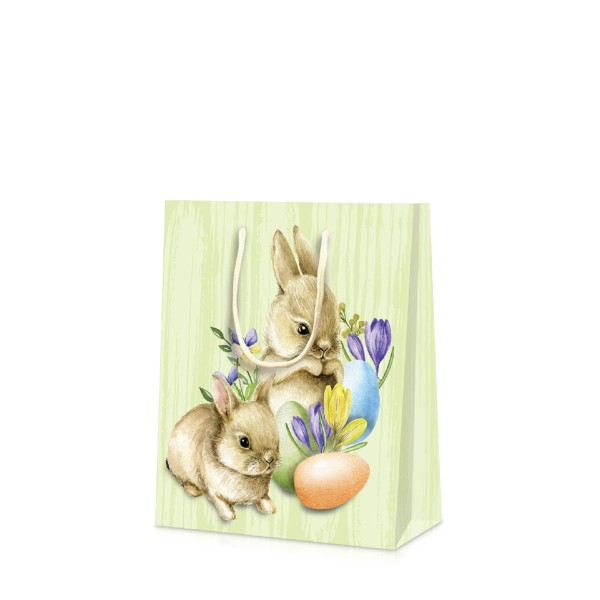 Kleine Tragetüte mit Kordeln und zwei niedlichen Osterhasen im Gras. 
